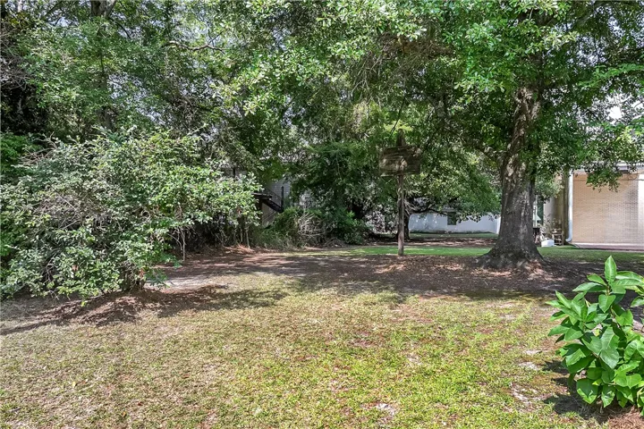 A spacious backyard with mature trees provides ample shade and privacy for outdoor enjoyment.