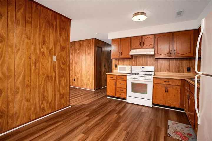 A functional kitchen features wood-paneled walls and a full suite of appliances, ideal for everyday meal preparation.