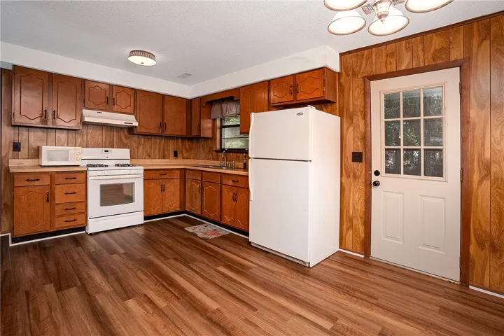 A well-appointed kitchen features ample wood cabinetry, full-size appliances, and durable plank flooring.