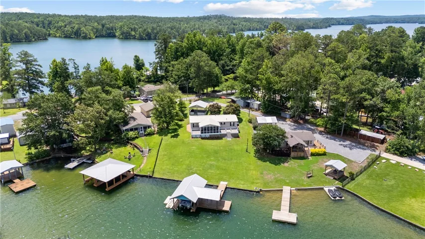 An aerial perspective reveals a serene lakefront property with a lush green lawn and private docks.