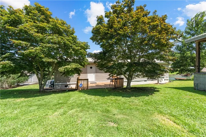 A quaint waterside retreat with a welcoming deck framed by mature shade trees.