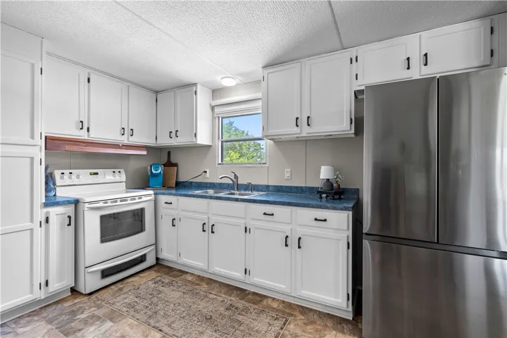 A well-lit kitchen with ample white cabinetry and dual sinks awaits your culinary adventures.