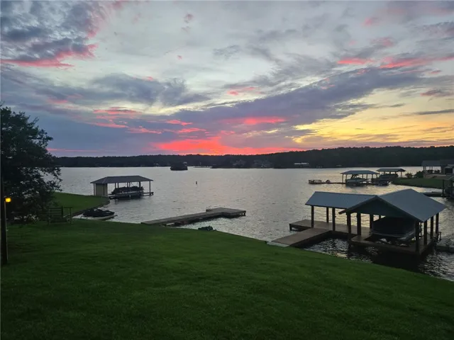 Observe tranquil lakefront living with covered boat docks against a vibrant sunset.