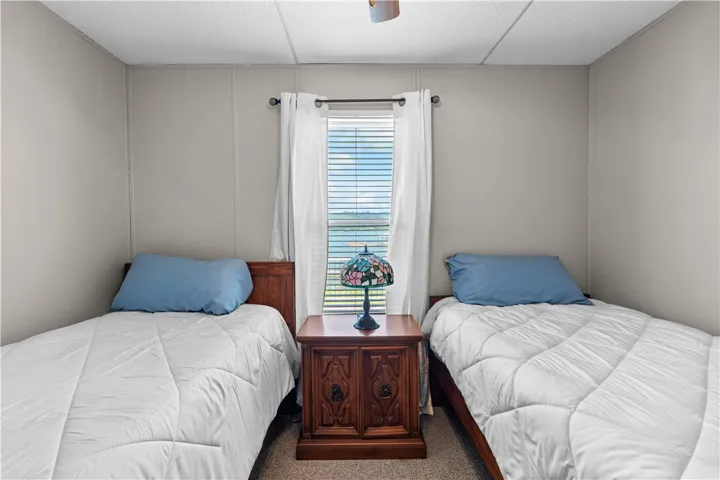 A well-lit bedroom offering tranquil views of the water from its window, ideal for peaceful slumber.