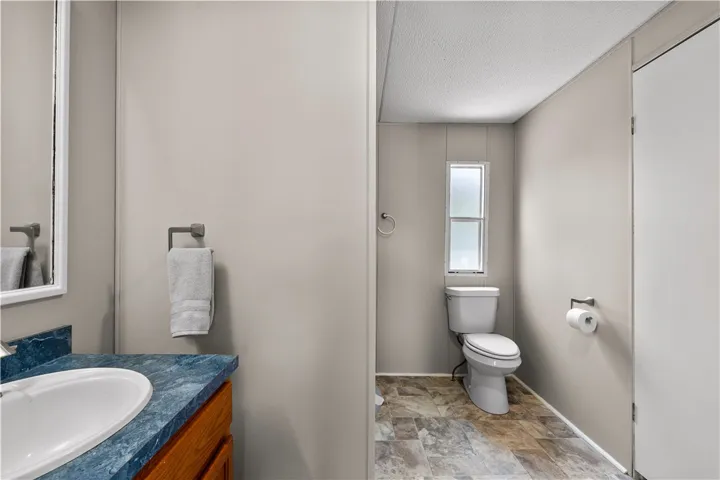 Functional bathroom features a blue marble-patterned vanity and tile-look flooring.