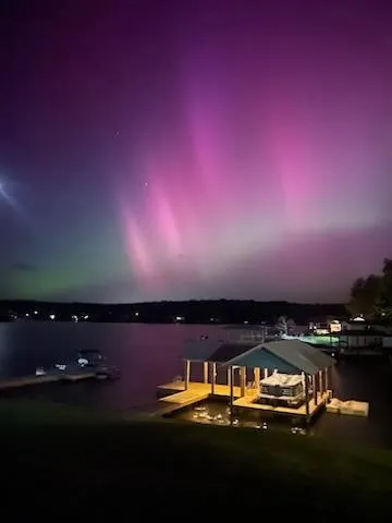 A private boat dock and covered slip await beneath an otherworldly, naturally illuminated night sky.