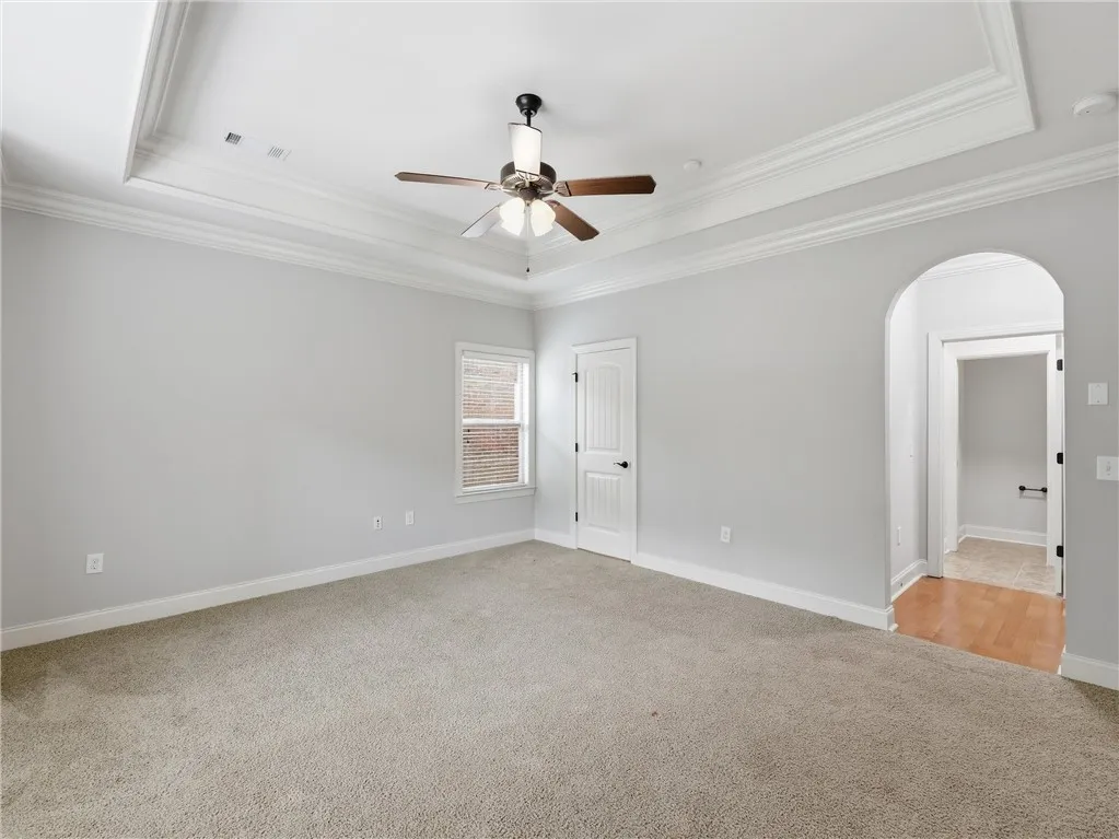 A quiet retreat with a classic tray ceiling, plush carpeting, and abundant natural light.