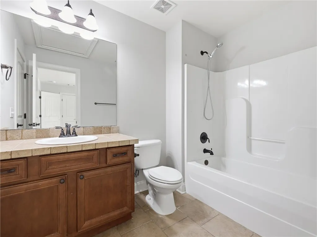 A well-appointed bathroom features a single vanity with stone counters and a practical tub/shower combination.