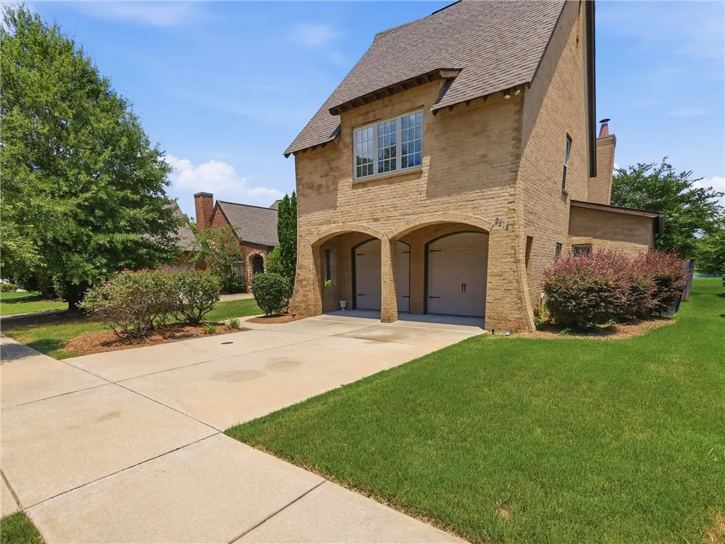 A charming brick exterior with arched garage entries and lush, well-maintained landscaping.
