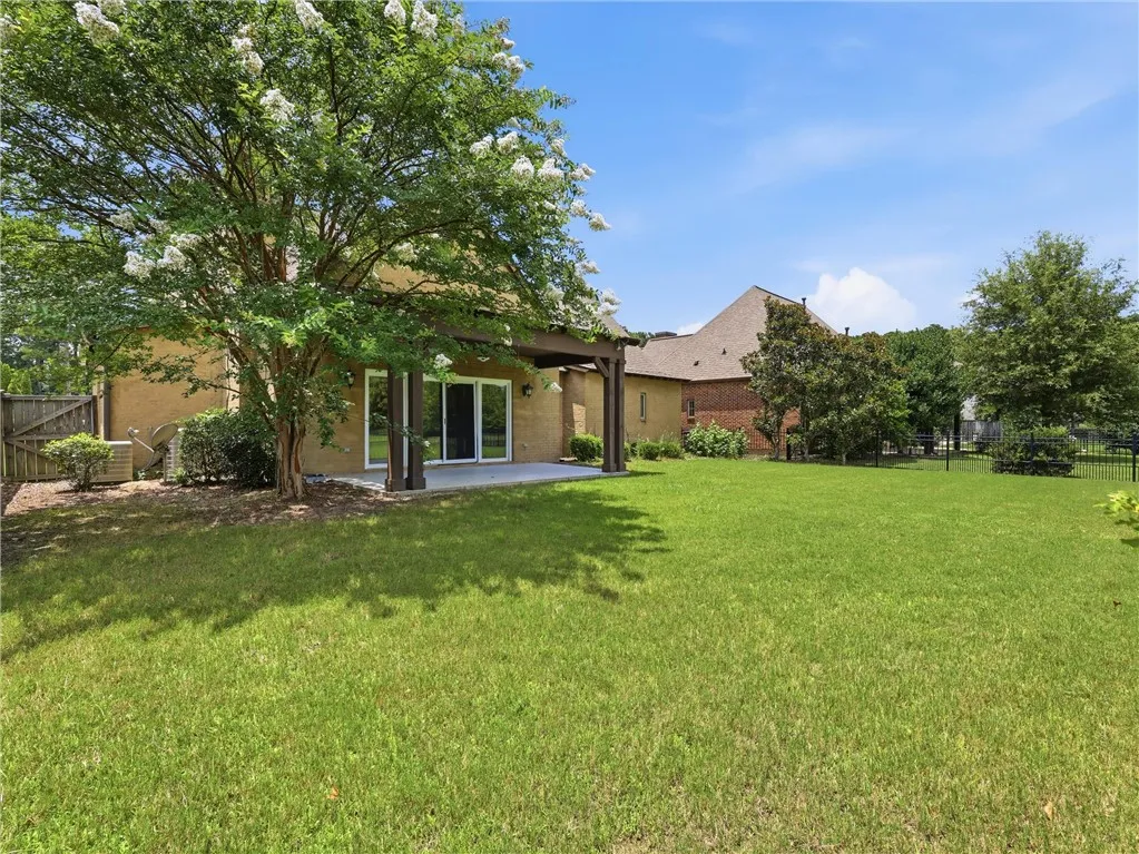 A sprawling backyard features a generous lawn and a covered patio for outdoor enjoyment.