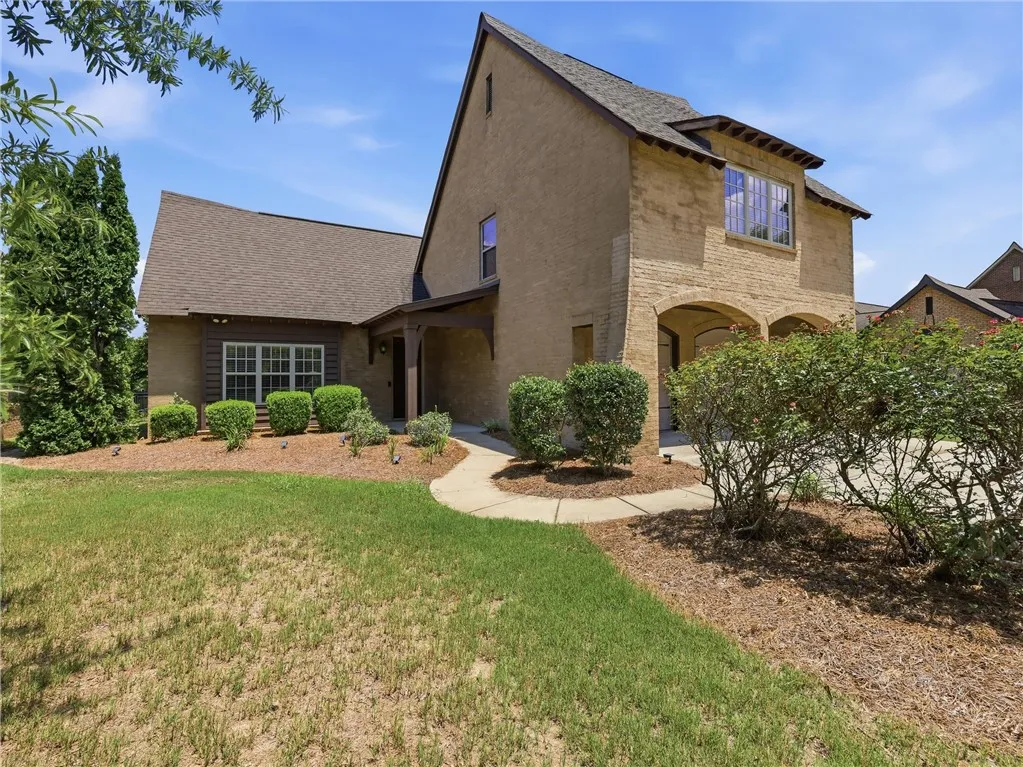 A graceful brick and stucco facade welcomes you home, boasting arched garage entrances and manicured shrubs.