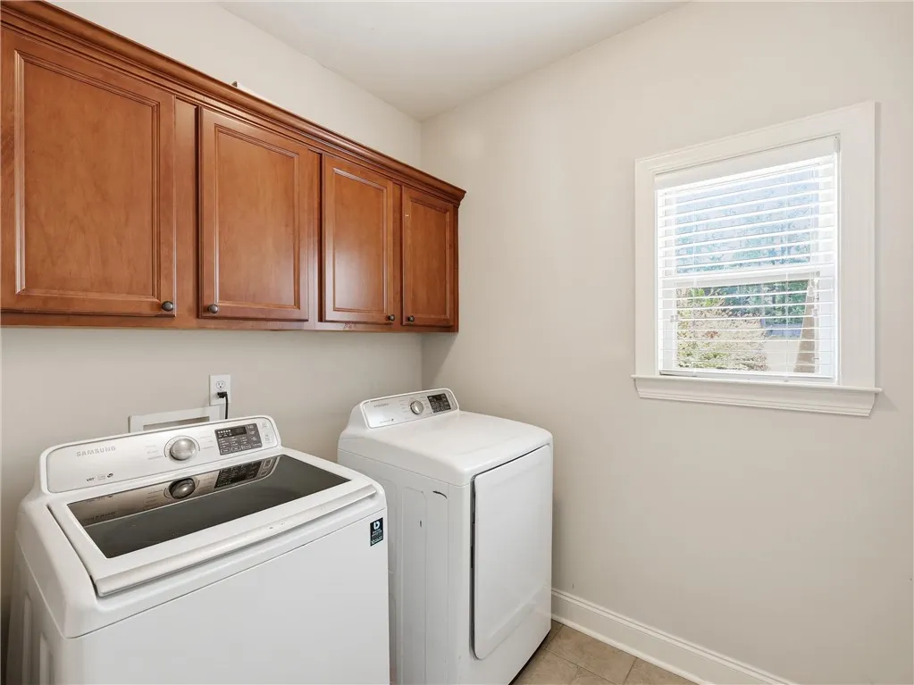 Convenient laundry space features upper cabinetry for storage and a naturally illuminated window.
