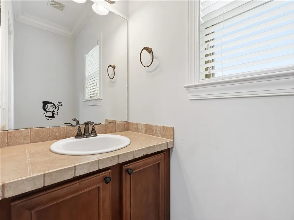 A well-appointed vanity with a tiled countertop and a spacious mirror creates a functional bathroom.
