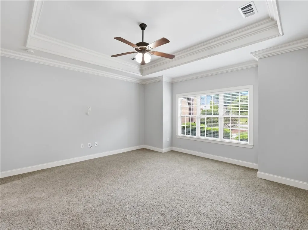 An airy bedroom with a tray ceiling and a comforting carpet, providing a tranquil retreat.