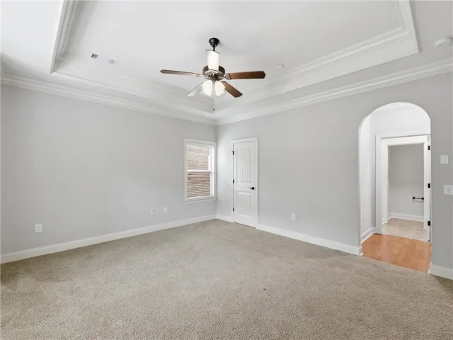 A quiet retreat with a classic tray ceiling, plush carpeting, and abundant natural light.