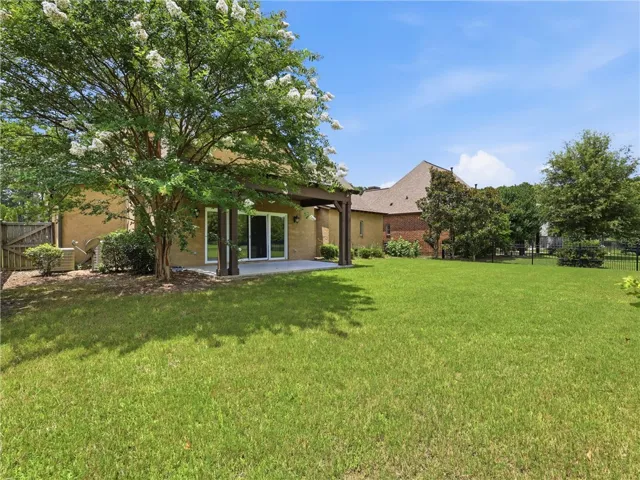 A sprawling backyard features a generous lawn and a covered patio for outdoor enjoyment.