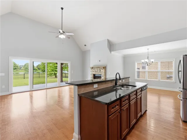 A striking open-concept layout unfolds with a grand fireplace, a well-appointed kitchen, and lake views through sliding glass doors.