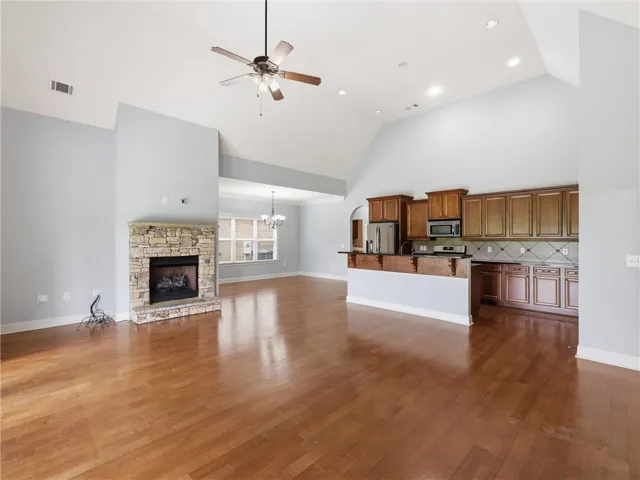 An inviting open-concept living area with soaring vaulted ceilings and a charming stone fireplace.