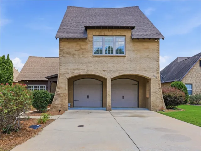A charming brick exterior with arched garage doors offers delightful curb appeal.