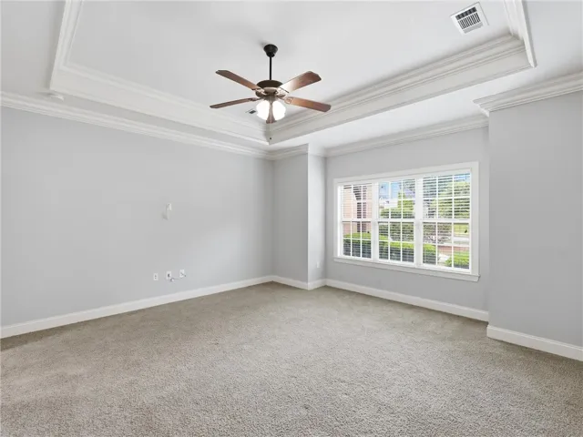 An airy bedroom with a tray ceiling and a comforting carpet, providing a tranquil retreat.