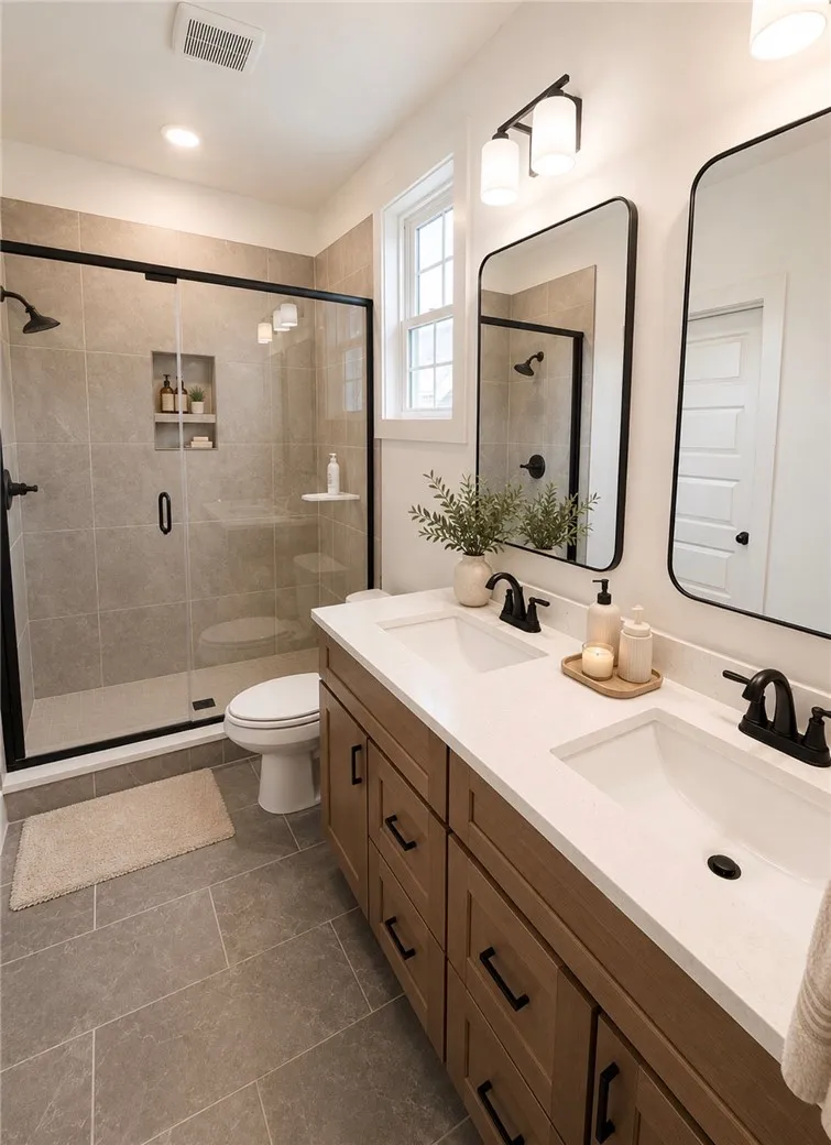 Dual vanities complement a spacious shower with sleek glass enclosure and contemporary fixtures.