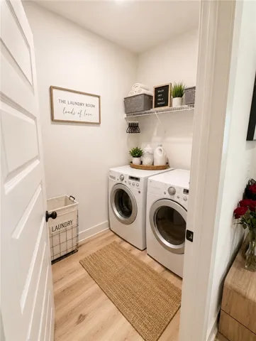Functional laundry space featuring modern appliances and light wood-tone flooring for easy care.