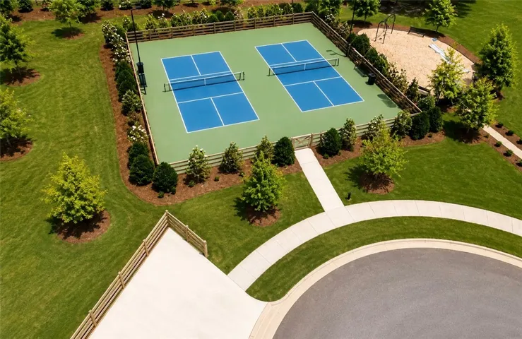 Two vibrant sports courts are ready for play, nestled within lush green landscaping and a welcoming pathway.