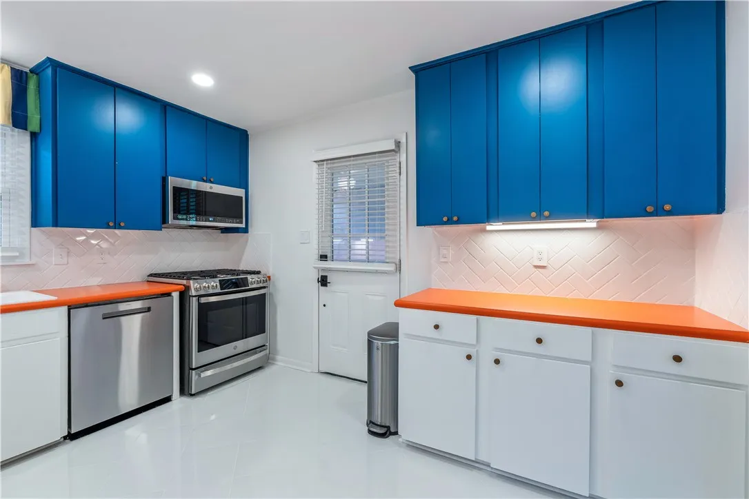 A vibrant kitchen features contrasting blue and white cabinetry with sleek stainless steel appliances.