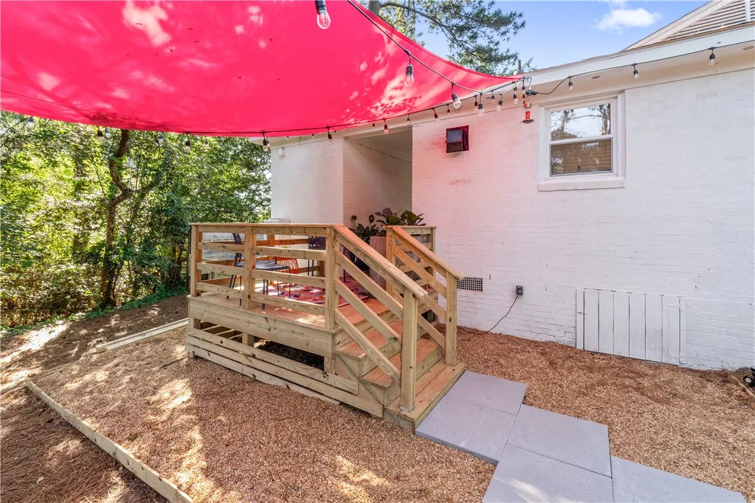 A spacious wooden deck with a vibrant red canopy provides a delightful outdoor retreat.