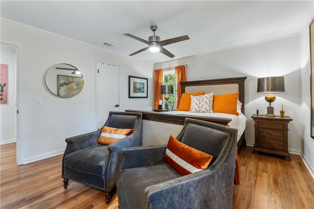 An inviting bedroom features rich hardwood flooring and a stylish ceiling fan for comfort.