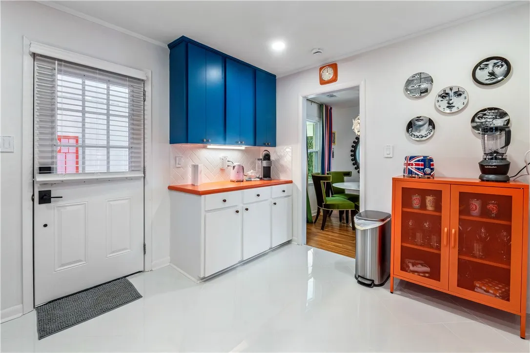 Bright white flooring extends through this cheerful kitchen, offering abundant cabinet storage and a Dutch door.