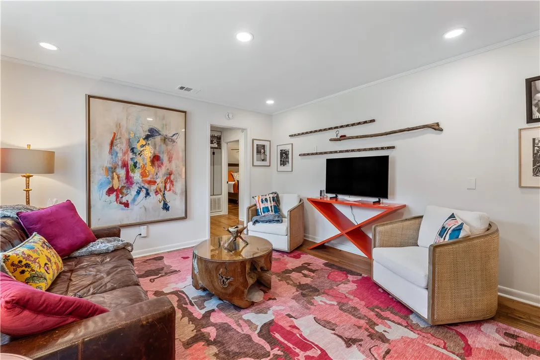 Bright recessed lighting illuminates this inviting living space, showcasing rich hardwood flooring and a vibrant area rug.
