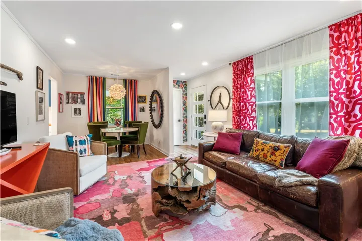 Recessed lighting illuminates an inviting living area with rich hardwood flooring and a charming dining space.