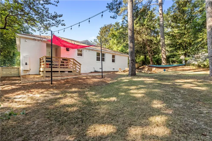 An inviting wooden deck extends to a generous backyard, ideal for outdoor gatherings and relaxation.