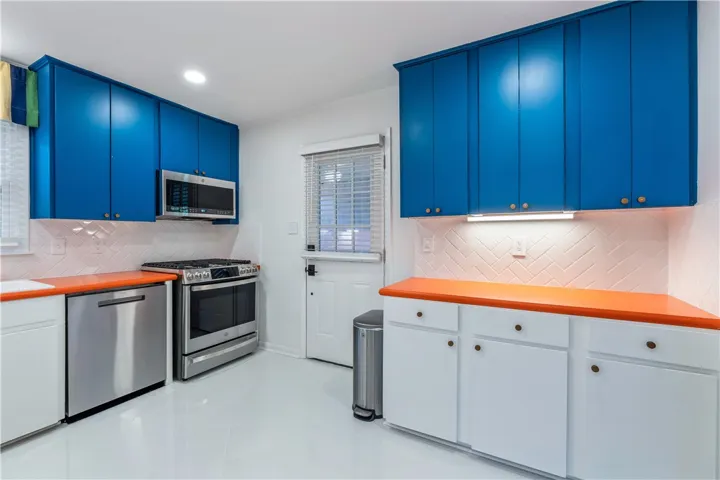 A vibrant kitchen features contrasting blue and white cabinetry with sleek stainless steel appliances.