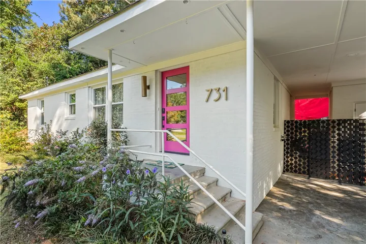 A vibrant fuchsia door provides a playful focal point to this charming single-story brick home.