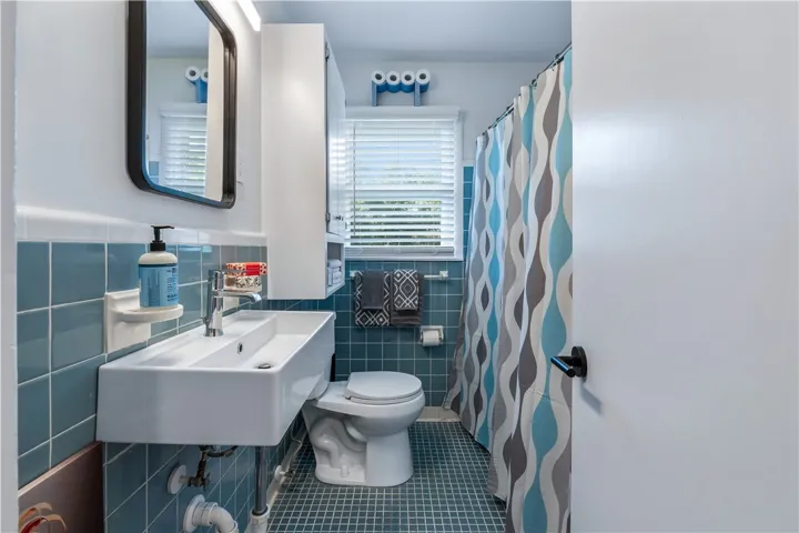 A vibrant bathroom with patterned blue tile and a modern floating sink.