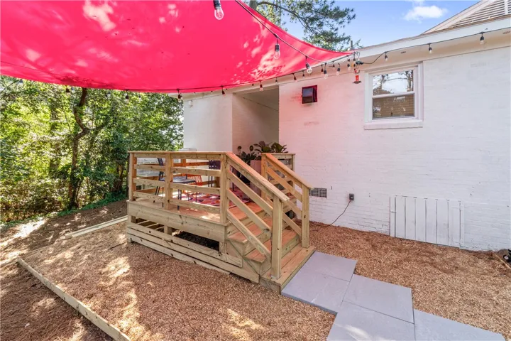 A spacious wooden deck with a vibrant red canopy provides a delightful outdoor retreat.