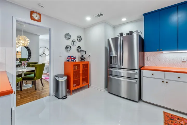 A vibrant kitchen features glossy floors, stainless steel appliances, and a seamless flow into the dining area.