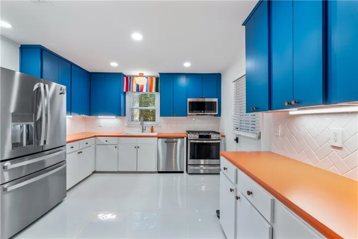 A well-lit culinary space showcases vibrant blue cabinetry and sleek stainless steel appliances.