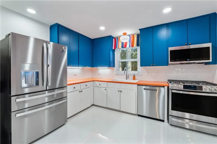 A well-lit kitchen boasts vibrant blue cabinetry, sleek stainless steel appliances, and ample counter space.