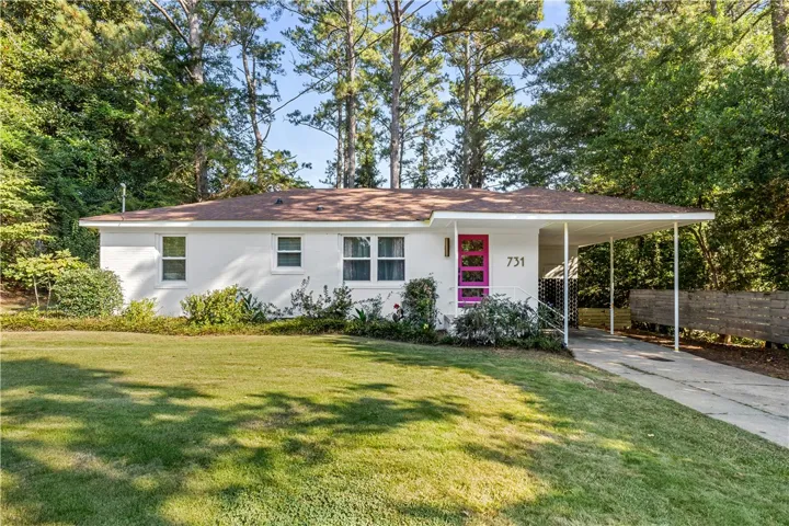 A charming single-level residence features a vibrant fuchsia front door and a convenient covered carport.