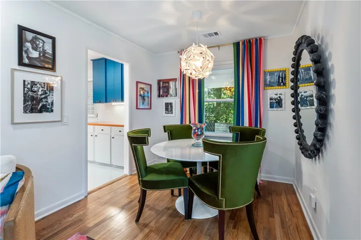 Hardwood floors flow through this dining area, featuring a decorative light fixture and colorful window treatments.