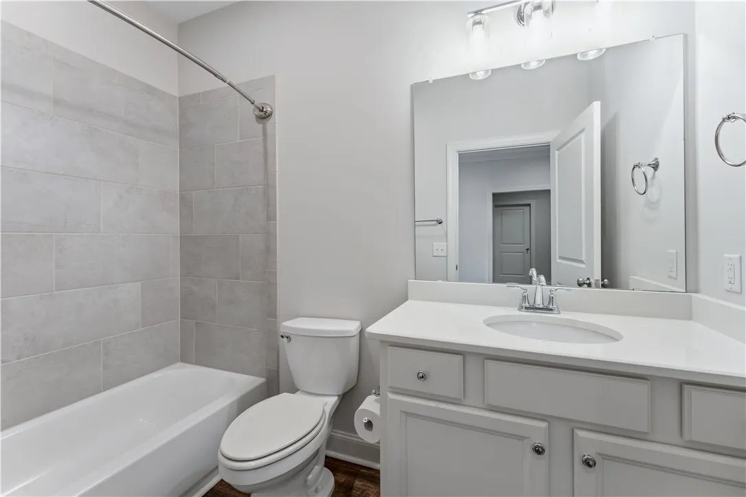 A well-appointed bathroom features a bathtub with tiled surround, a toilet, and a vanity with a large mirror.