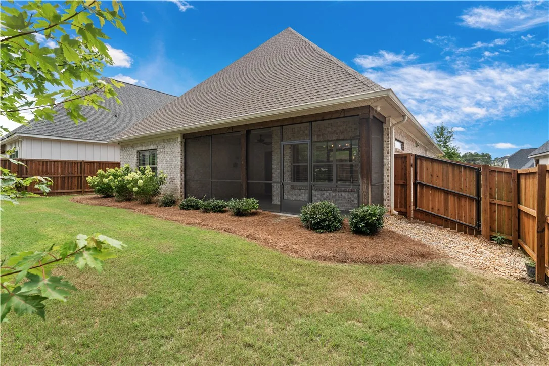 A private, fenced backyard features a covered, screened porch, ideal for enjoying outdoor living.