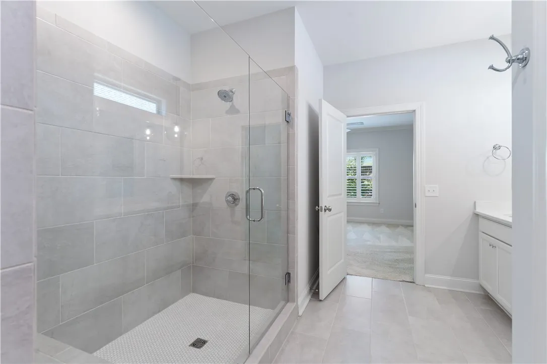 A well-lit, tiled shower with clear glass enclosure and built-in shelving offers a clean, functional bathing space.