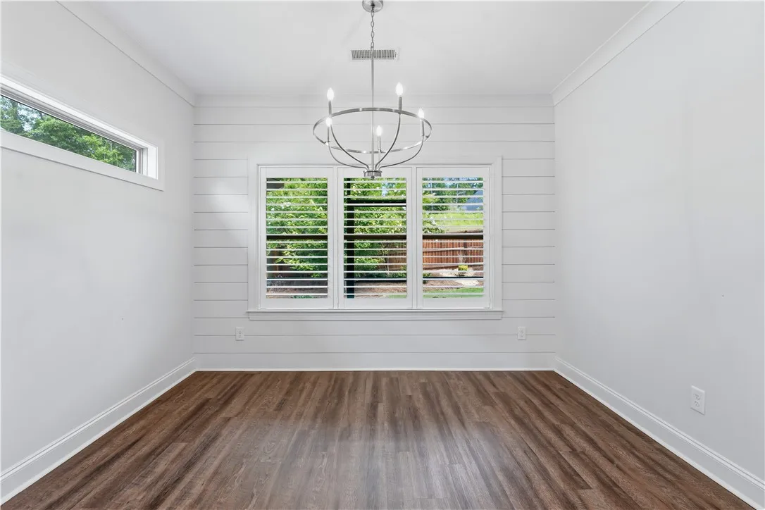 A refined dining space features durable wood flooring and elegant plantation shutters.
