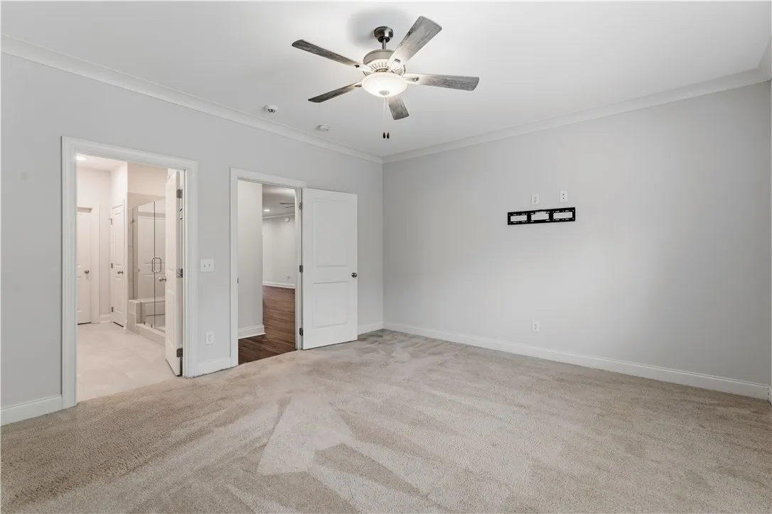 A quiet retreat with plush carpeting and modern ceiling fan, offering a seamless transition to an adjacent bath and additional living space.