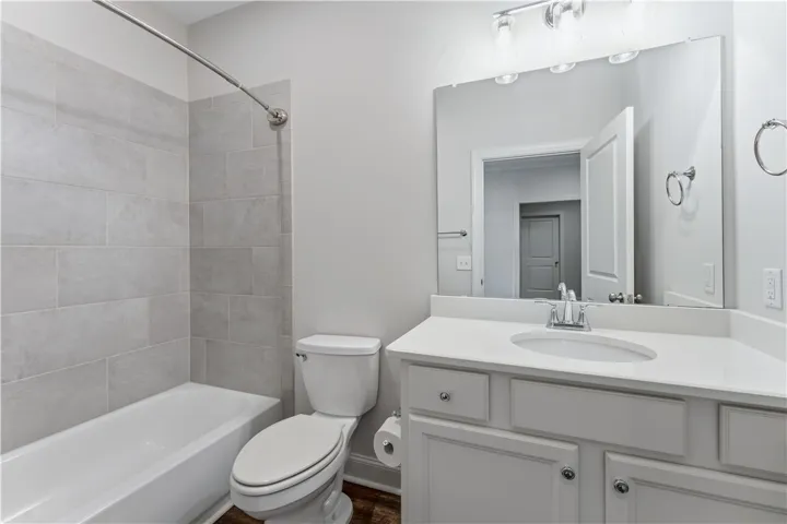A well-appointed bathroom features a bathtub with tiled surround, a toilet, and a vanity with a large mirror.