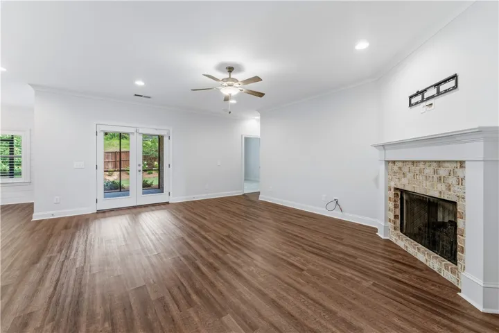 A generous living space featuring warm wood flooring and a classic brick fireplace hearth.